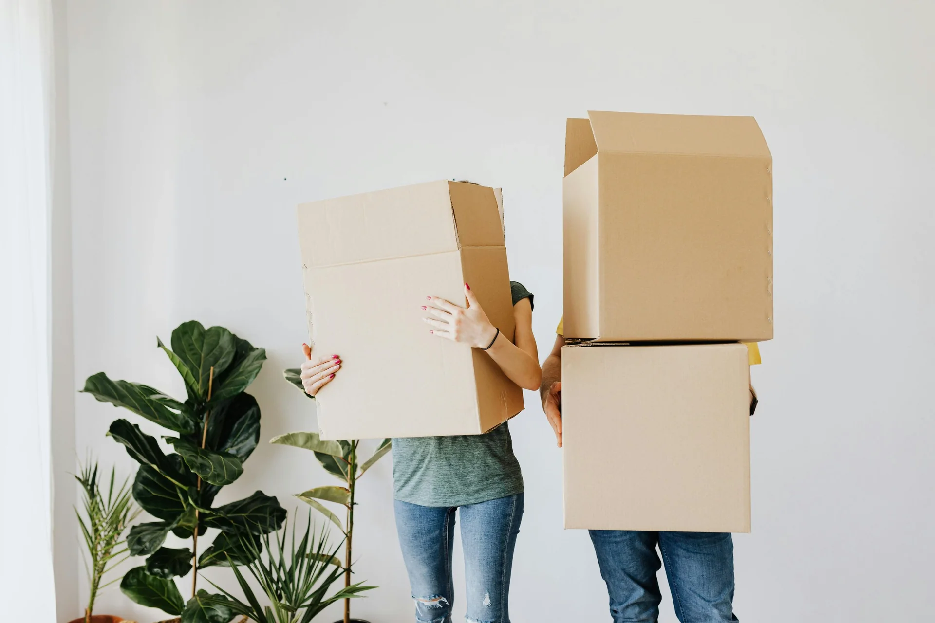 Couple carrying moving boxes into a home