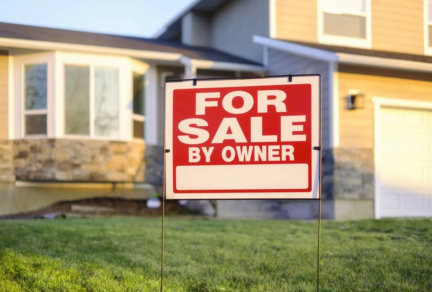 For sale by owner sign in front of a house