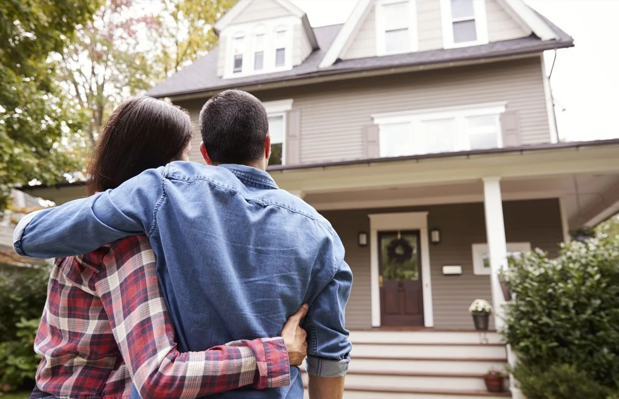 Couple standing together in front of a home